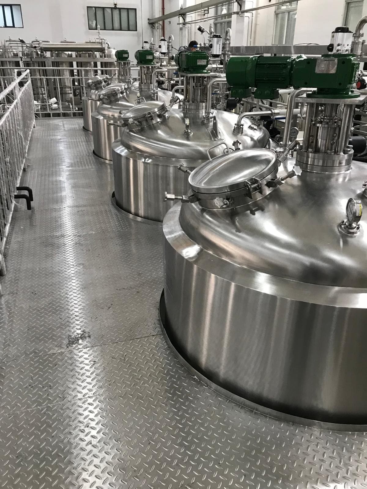 A row of polished stainless steel process vessels with agitators at a Petro Sep plant.